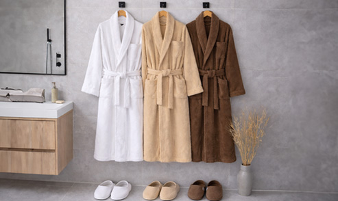 Luxury bathrobes in neutral shades hanging in a serene modern bathroom interior.